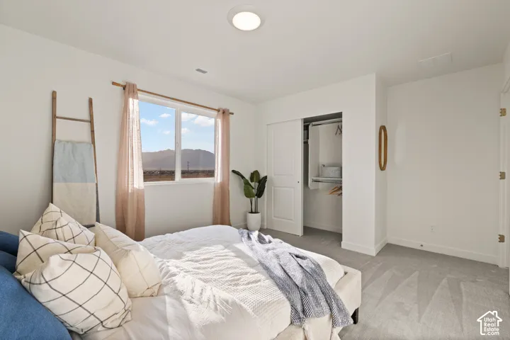 Recessed lighting, large window, mountain scenery, sliding closet doors, and light gray carpeting