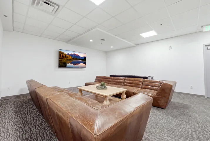 Recessed ceiling lighting, dropped ceiling grid, wall-mounted television, and carpet flooring