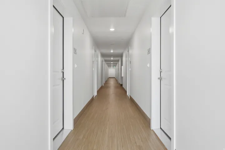 Extended hallway with wood-finish flooring, white walls, and recessed lighting