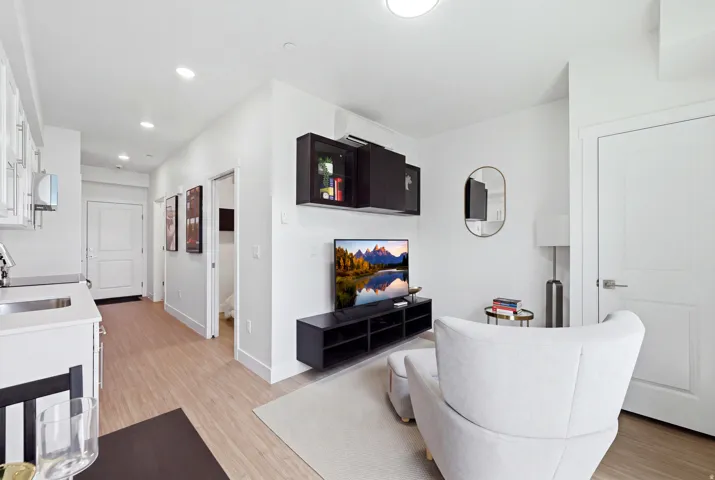 Recessed ceiling lighting, wood-finish flooring, white flat-panel doors, white walls, and built-in wall cabinetry