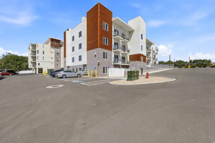 Multi-story building featuring white and wood-finish siding, stone-finish accents, and multiple balconies