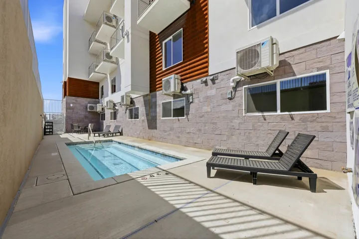 Outdoor plunge pool with integrated steps, concrete surround, and adjacent stone veneer wall