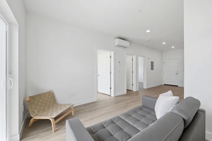 Recessed lighting, wood-finish flooring, white walls, multiple interior doors, and a mounted climate control unit