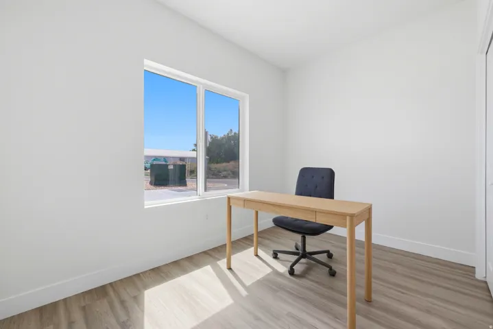 Recessed lighting, wood-finish flooring, white walls, and a window with white trim