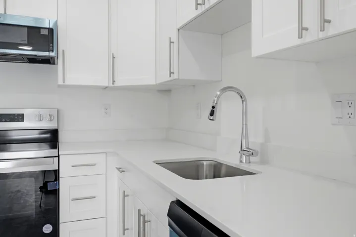 Contemporary kitchen with white cabinetry, stainless steel appliances, and a single basin sink with a pull-down faucet