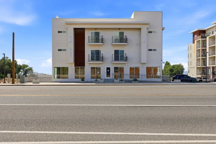 Contemporary multi-story building featuring a smooth stucco exterior with wood-finish panel accents