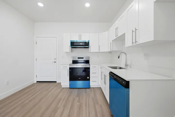 Kitchen featuring white cabinetry, light-toned wood-finish flooring, white countertops, and stainless steel appliances