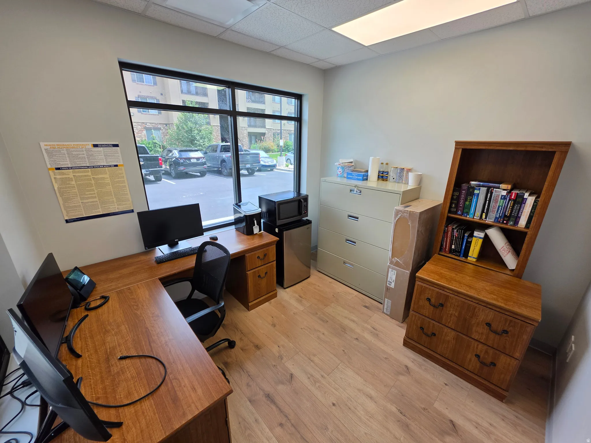 Light-colored walls, wood-finish flooring, a large window, and recessed lighting