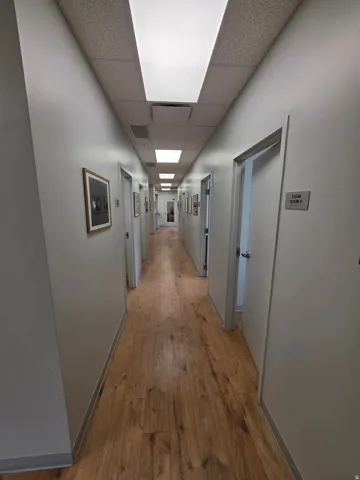 Long hallway featuring wood-finish flooring, white walls, and recessed lighting