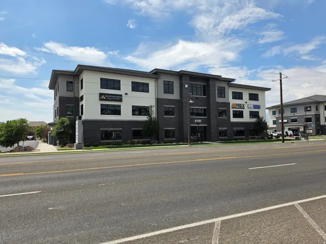 Modern commercial building featuring a multi-tone facade, prominent street number signage, and extensive windowing