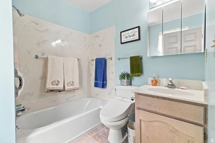 Full-sized bathtub with a shower head, patterned wall surround, integrated sink vanity with a wood-finish cabinet, and a mirrored medicine cabinet
