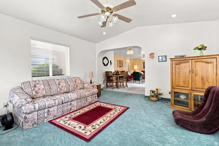 Recessed lighting, arched doorway, ceiling fan, window with horizontal blinds, and a built-in wooden cabinet