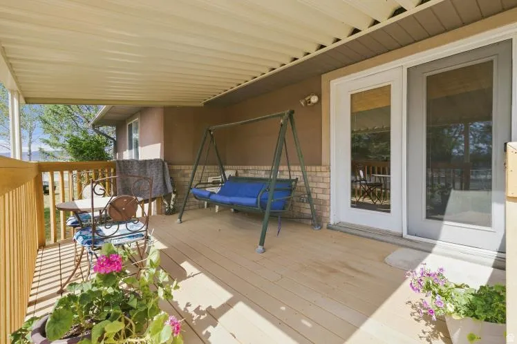 Covered deck featuring wood-finish flooring, wood railing, and brick accent wall