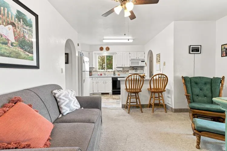 Open-concept living space with carpeted flooring and an arched entryway