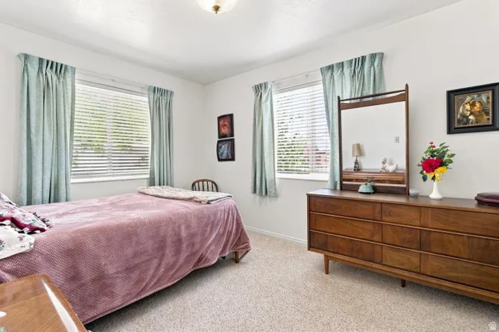 Neutral-toned wall-to-wall carpeting, white walls, two windows with blinds, and a ceiling-mounted light fixture