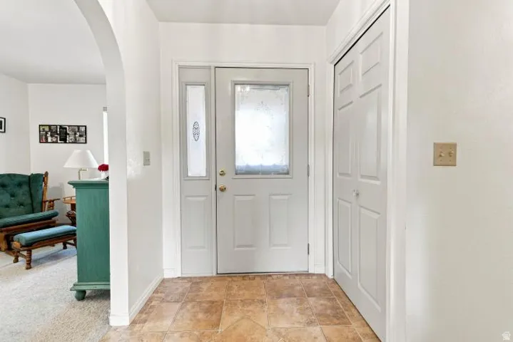 Entryway featuring a paneled door with frosted glass, a frosted glass sidelight, a bi-fold closet, and neutral tile flooring