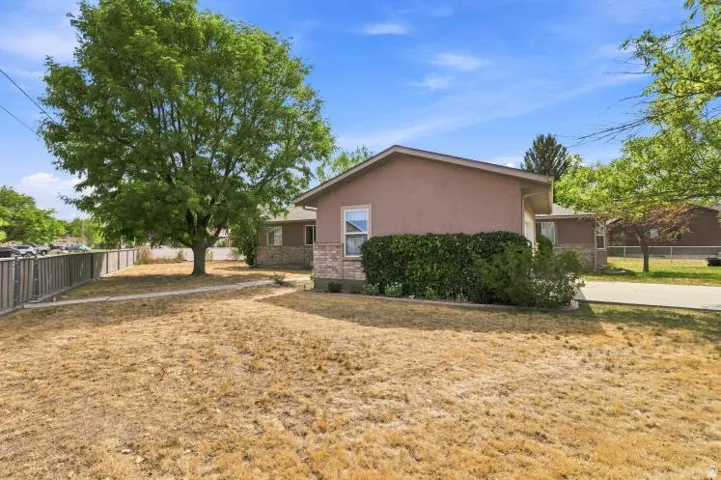 Stucco exterior with stone accent detailing, mature trees, and established landscaping
