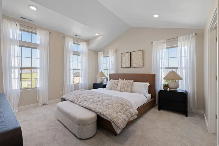 Vaulted ceiling with recessed lighting, large paneled windows, light-toned carpeting, and a built-in closet
