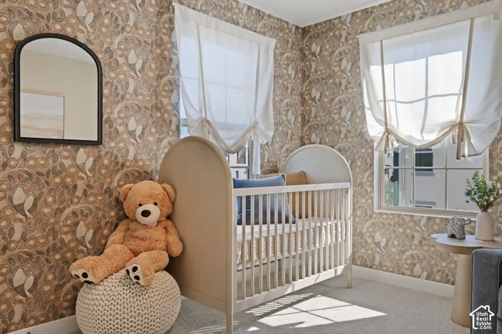 Patterned wallpaper with an arched mirror, two windows with Roman shades, and carpeting