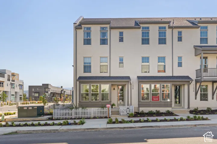 Multi-level townhome featuring a neutral-toned exterior, dark-trimmed windows, and a front porch