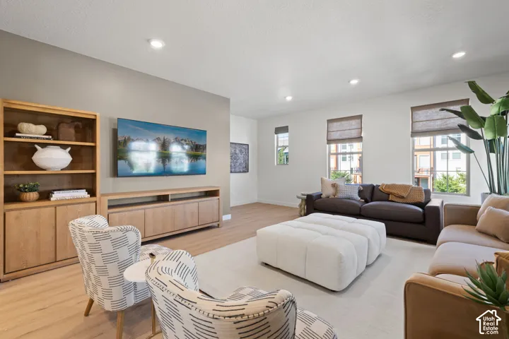Recessed lighting, wood-finish flooring, built-in media console, multiple windows with window treatments, and light wall paint