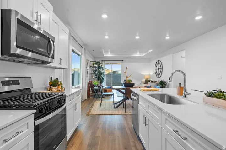 Gourmet kitchen featuring stainless steel appliances, white cabinetry, undermount sink, and light-toned countertops