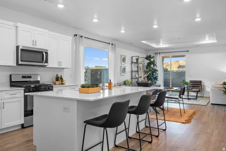 Open-concept kitchen with white cabinetry, stainless steel appliances, and a central island with a solid surface countertop