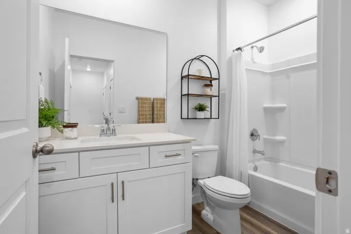 White vanity with a single basin sink, white countertop, and wood-finish flooring