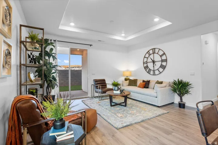 Recessed lighting, tray ceiling, wood-finish flooring, sliding glass door, and a paver patio