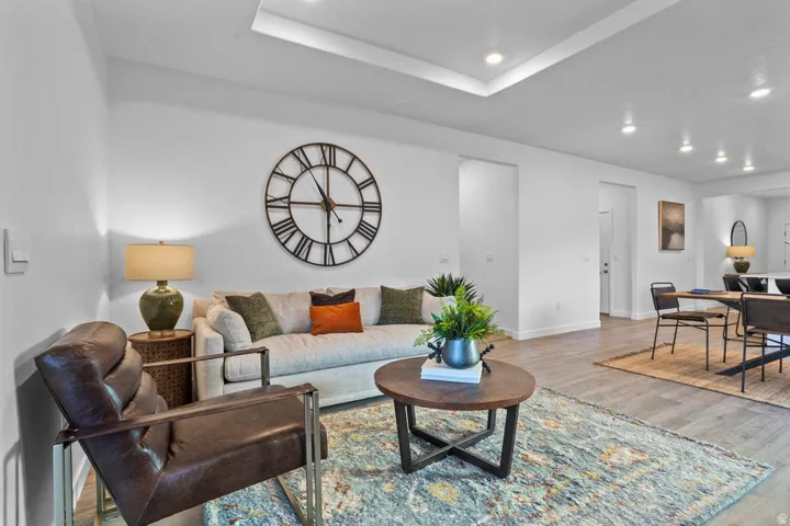 Recessed lighting, tray ceiling, light wood-finish flooring, white wall finishes, and open doorways