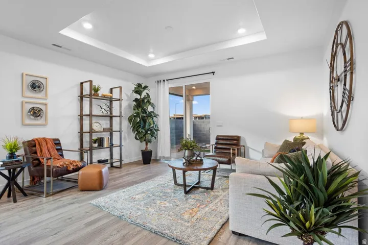 Recessed lighting, tray ceiling, wood-finish flooring, sliding glass door, and a built-in shelving unit