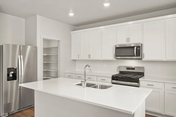 **DISCLAIMER**   Interior package upgrades not photographed. White cabinetry with stainless steel hardware, white countertop surfaces, stainless steel appliances, and a white tile backsplash