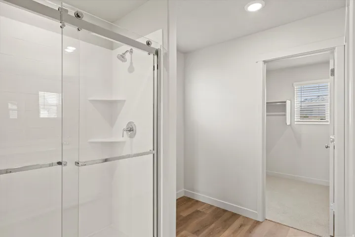 **DISCLAIMER**   Interior package upgrades not photographed. Walk-in shower with sliding glass doors, chrome fixtures, and built-in shelving