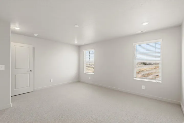**DISCLAIMER**   Interior package upgrades not photographed. Carpeted room featuring multiple windows with blinds, recessed lighting, and a white interior door
