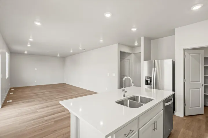 **DISCLAIMER**   Interior package upgrades not photographed. Open-concept living space featuring wood-finish flooring, recessed lighting, and a kitchen island with a double basin sink