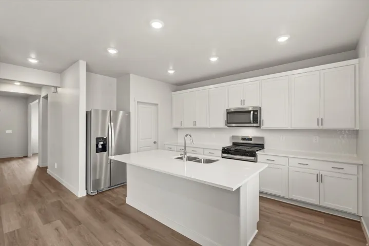 **DISCLAIMER**   Interior package upgrades not photographed. Kitchen featuring white cabinetry, stainless steel appliances, a center island with an integrated sink, and recessed lighting