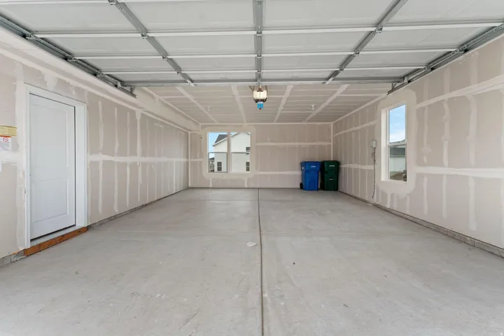 Spacious garage featuring a concrete floor, overhead lighting, and an interior access door