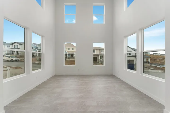 Two-story ceiling, multiple large windows, light gray flooring, white walls, and white trim