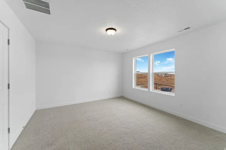 Carpeted room with white walls, two double-hung windows, and a flush mount ceiling light