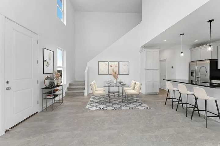 Open-concept living space featuring soaring vaulted ceilings with skylights, gleaming wood-finish flooring throughout, and a chef's kitchen with stainless steel appliances and island seating