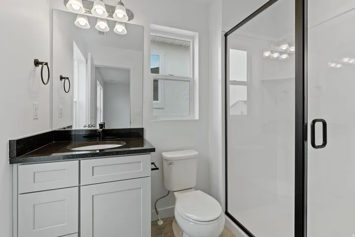 Modern bathroom featuring a white vanity with dual drawers, black countertop, and integrated sink