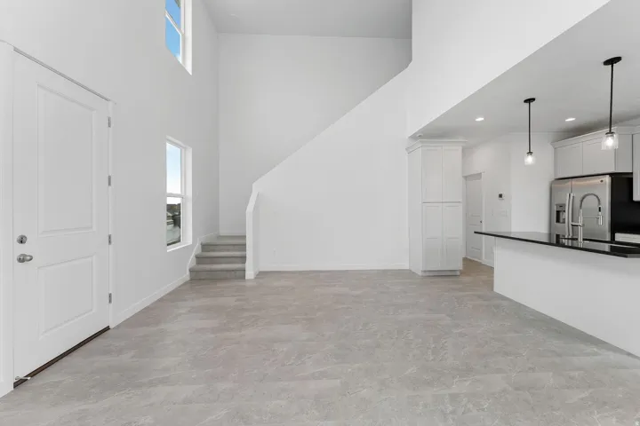 Open-concept living space with high ceilings, large windows, and gray-toned tile flooring