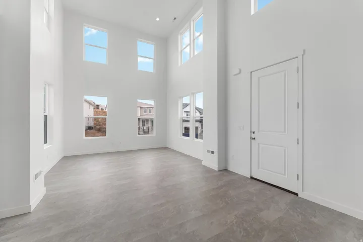 Bright, open foyer showcasing soaring ceilings with abundant natural light from multiple windows, polished concrete flooring, and clean white wall surfaces
