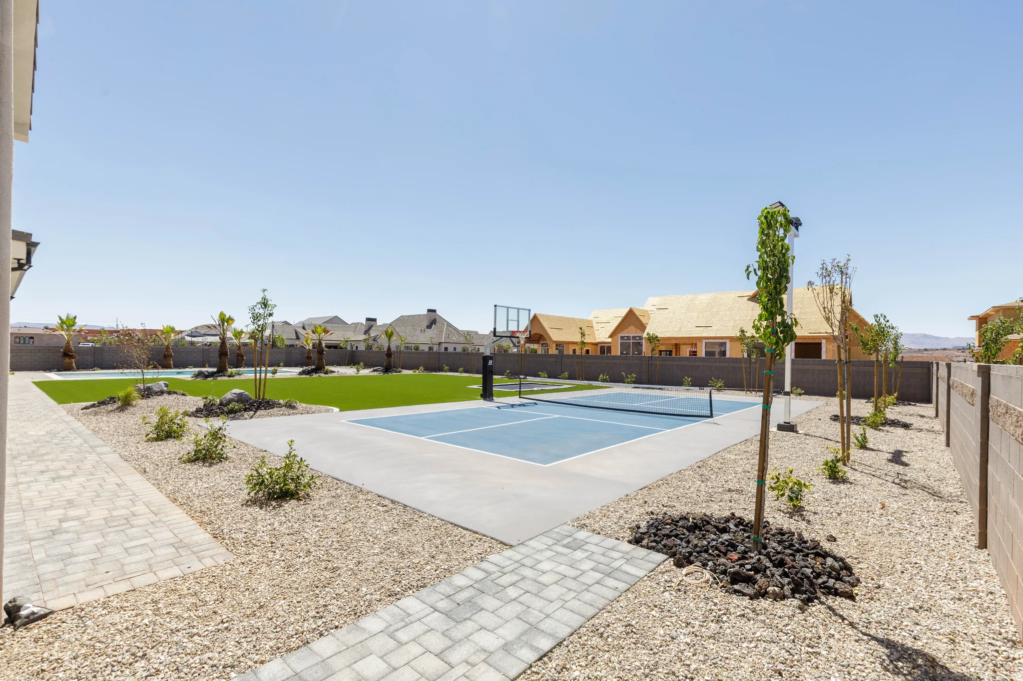 Expansive outdoor area featuring a paved patio, a sport court, a swimming pool, and a gravel landscape