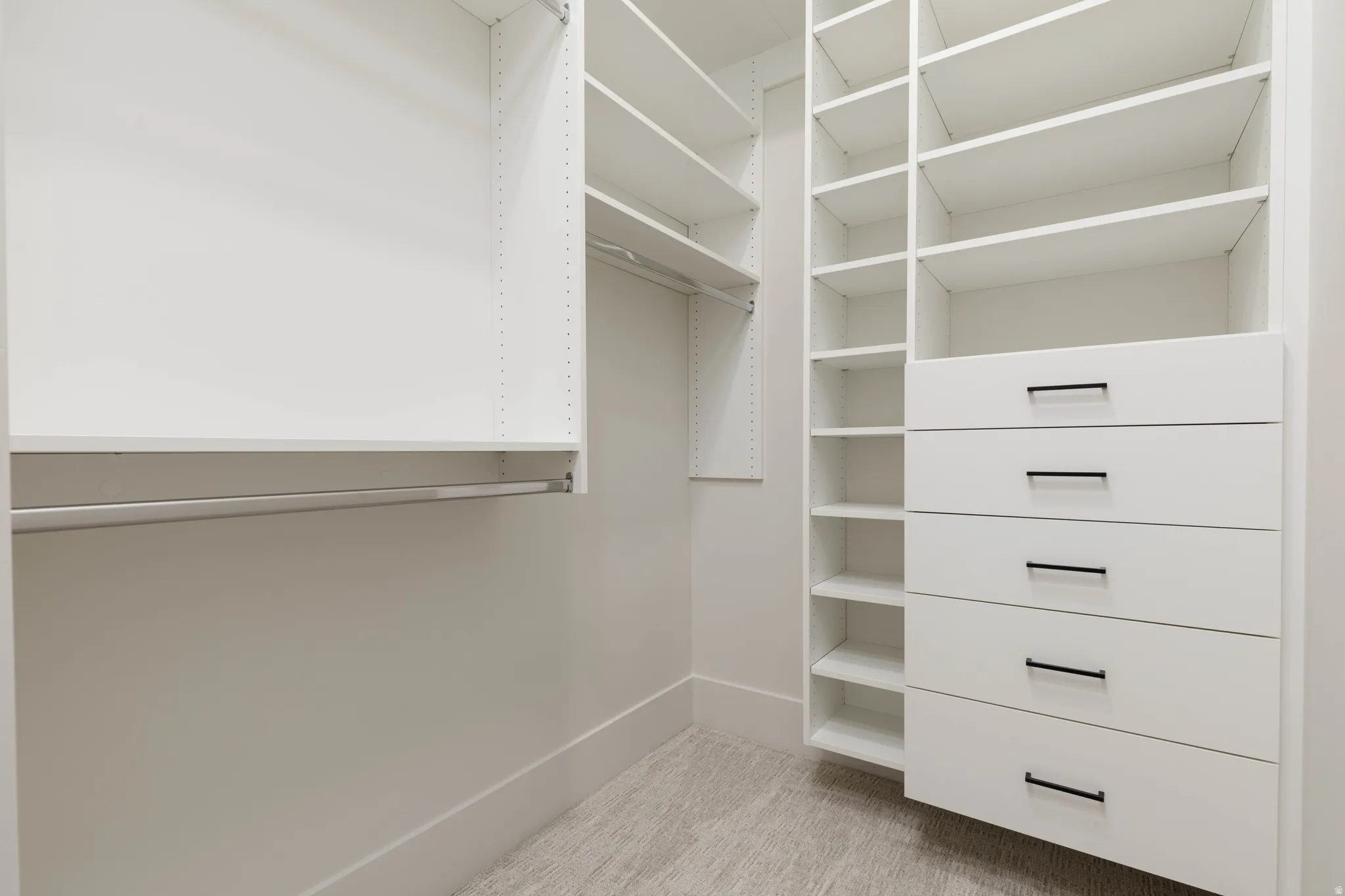 White custom closet system featuring multiple shelves, hanging rods, and built-in drawers with matte black hardware