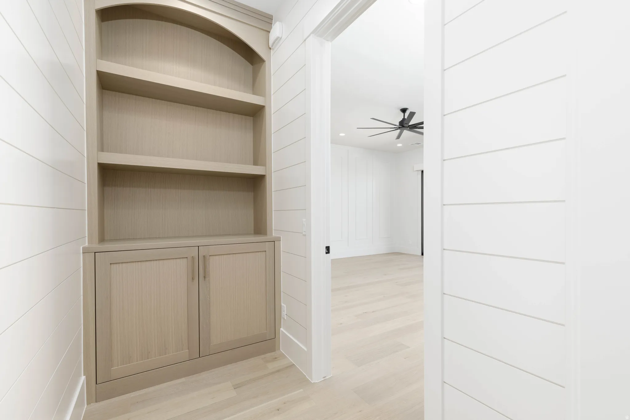 Built-in shelving with lower cabinetry, shiplap wall paneling, and wood-finish flooring
