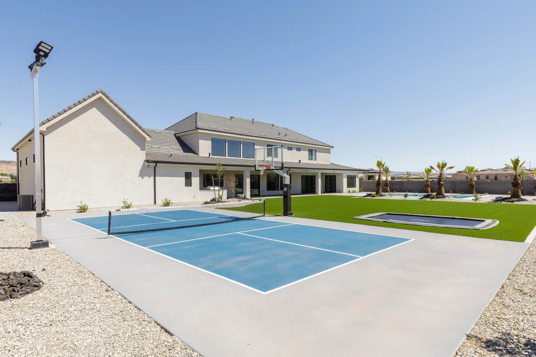 Expansive concrete sports court, integrated basketball hoop, and artificial turf lawn