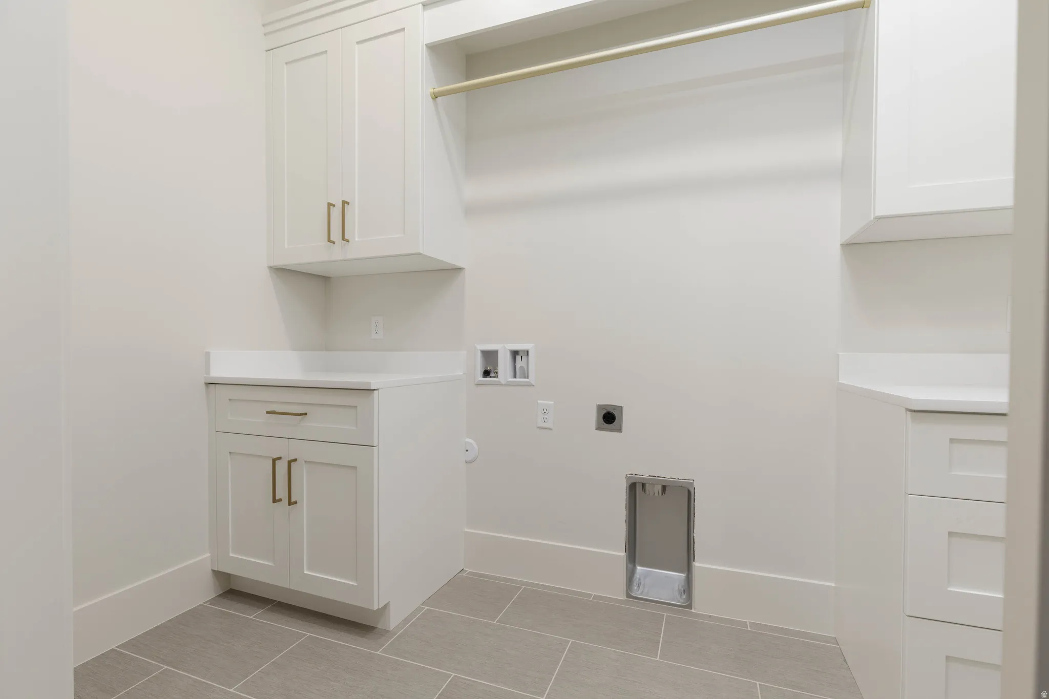 White cabinetry with gold-finish hardware, light-toned countertop, and tile flooring