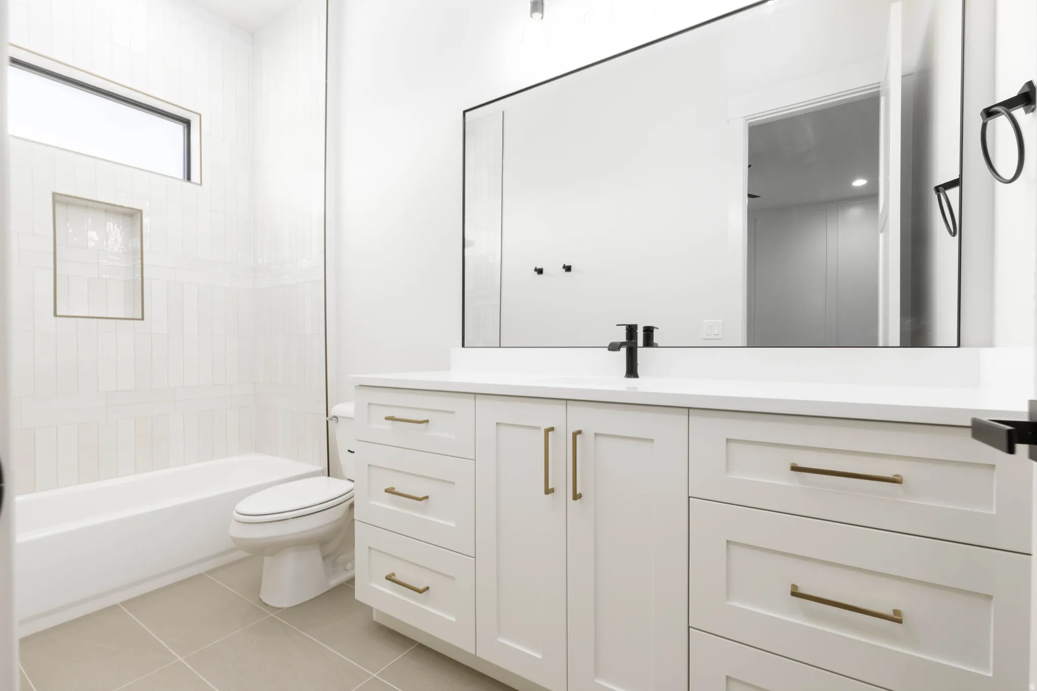 White vanity with bronze hardware, a contrasting black faucet, and a large mirror