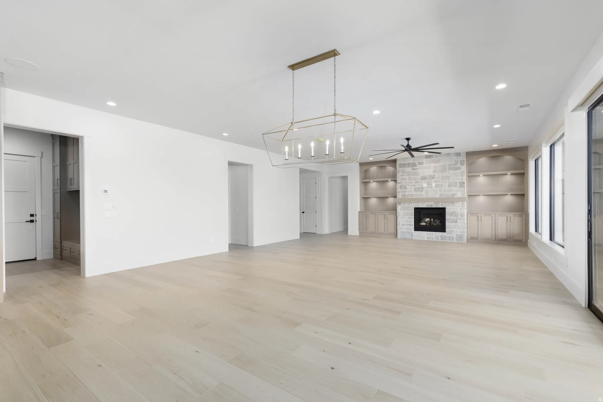 Vaulted ceilings, wood-finish flooring, stone fireplace, built-in cabinetry with shelving, and large windows